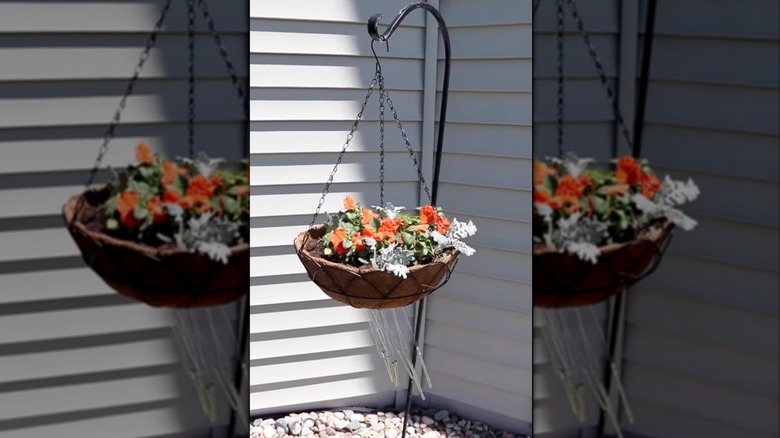 Hanging pot with wind chimes on a shepherds hook near the corner of a house