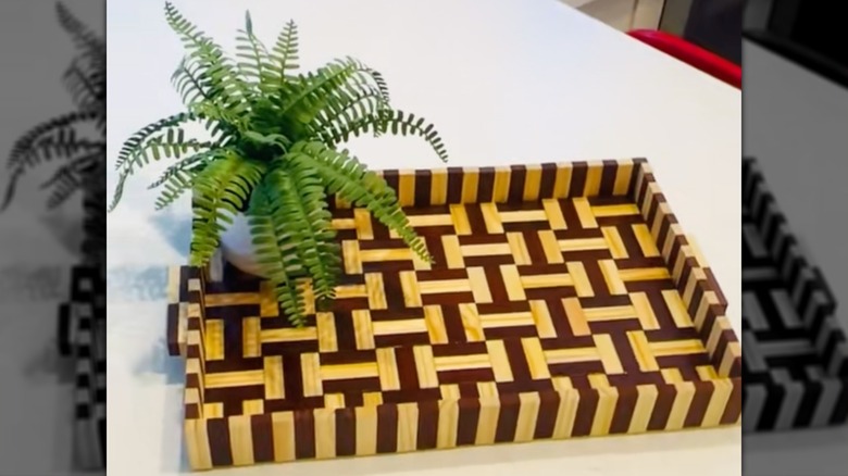 Decorative tray made from alternating dark and light wood blocks with plant