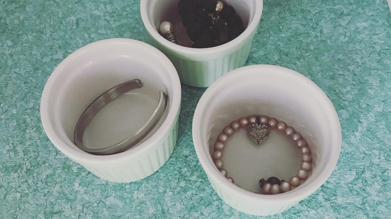 Three ramekins in white filled with jewelry