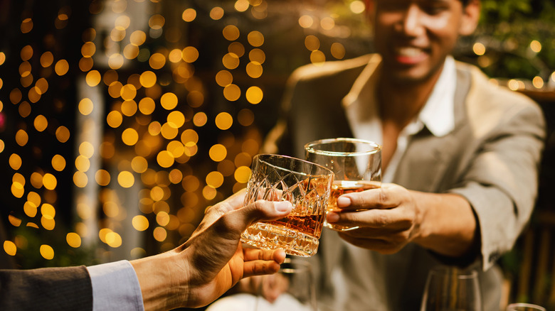 Two men clinking glasses cheering holiday party