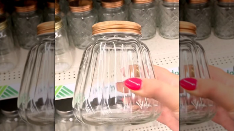 A person holding a Dollar Tree pumpkin shaped glass jar