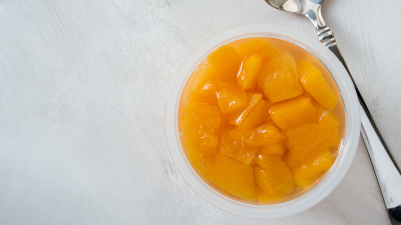 closeup of peaches in fruit cup beside spoon