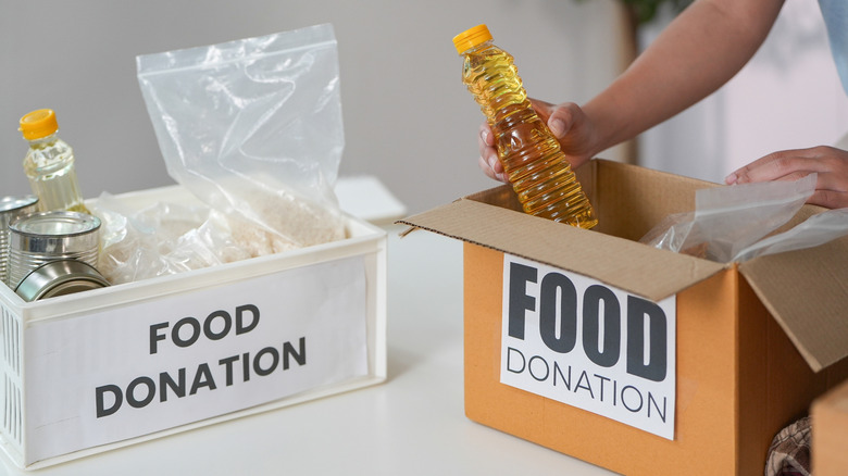 person placing cooking oil into food donation box