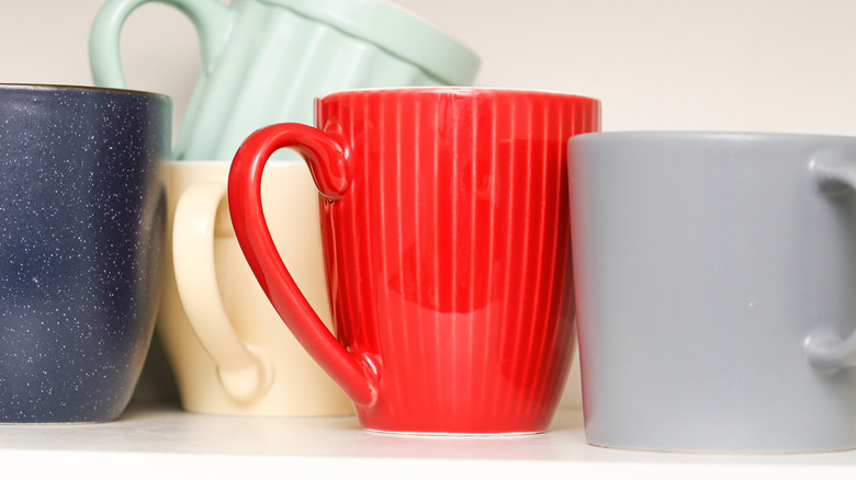 colorful mugs lined up in cabinet