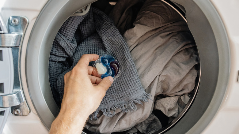 Man about to place detergent pod inside washing machine