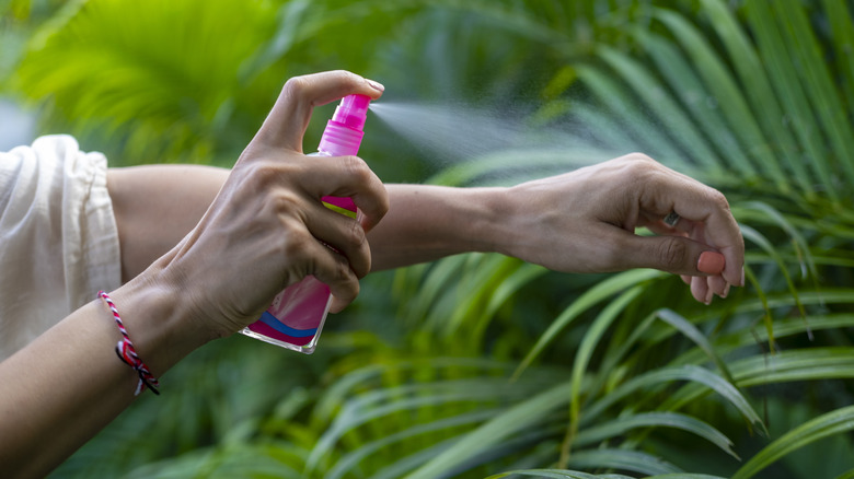 A female is spraying an insect repellent on her arm