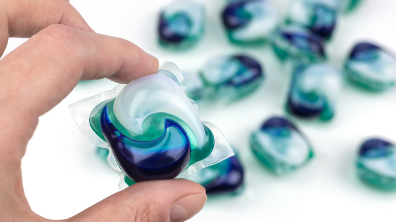 A person holding up a laundry pod over a collection of laundry pods