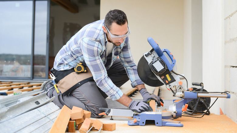 Man using a saw to cut wood deck boards and install a deck
