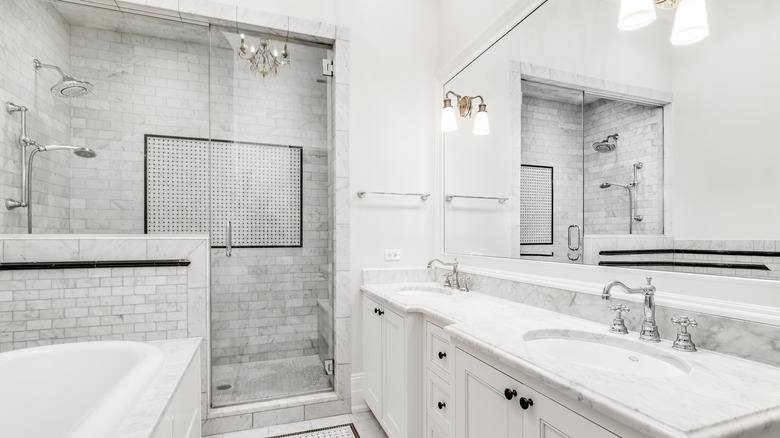 Narrow bathroom with white floors, walls, bath, shower, sink, and cabinets