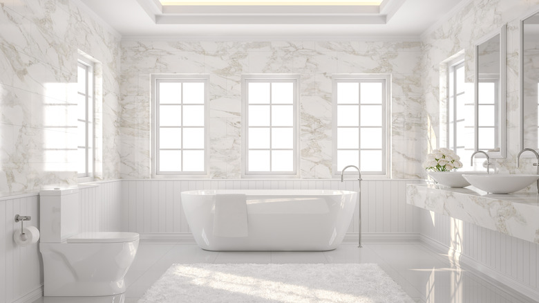 Modern bathroom with a toilet, bath tub, and sink with a floor covering and flowers