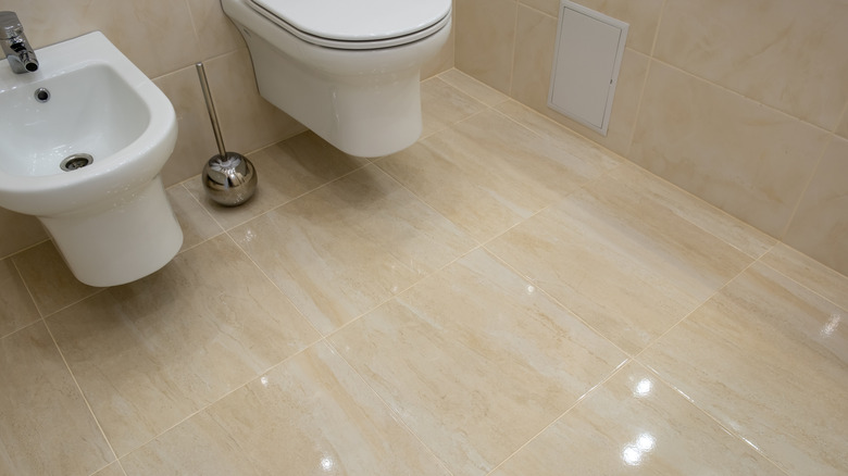 Beige tiled bathroom with glossy finish that reflects the ligtht
