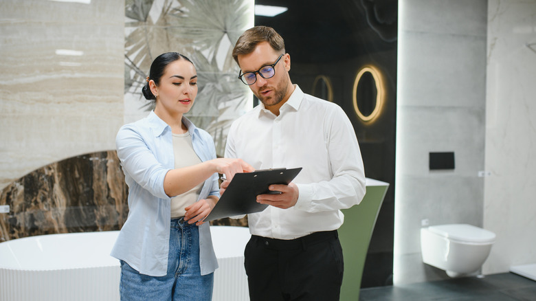 Man and woman looking at a clipboard in a modern bathroom