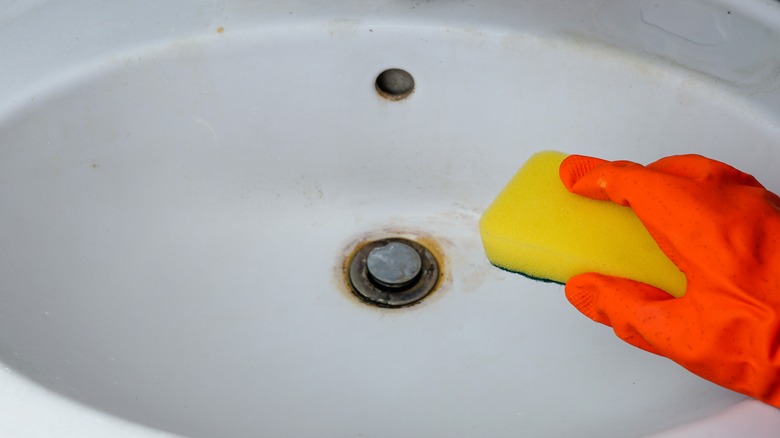 hand holding sponge over sink