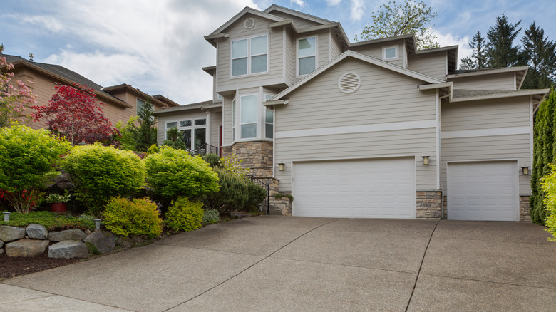 A beautifully-maintained driveway outside of a two-story beige home.