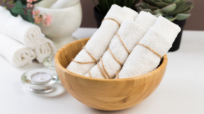 Brown bamboo bowl with rolled white towels inside