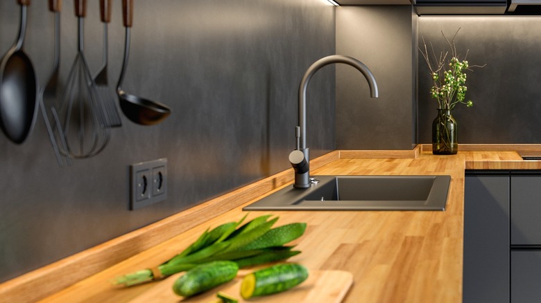 modern black kitchen with black sink in wood countertop with backsplash