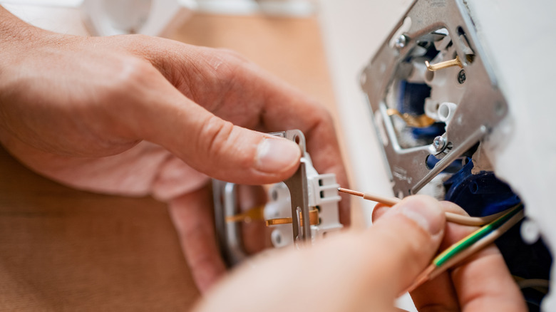 Hand connecting new wiring in a power outlet