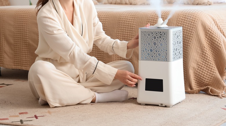 Woman sitting next to a white humidifier in a bedroom