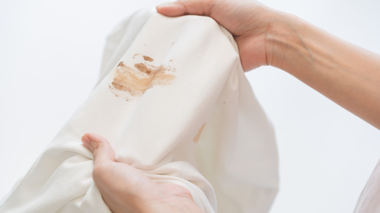Hands holding a stained white clothing