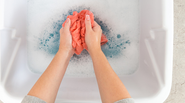 Hands washing clothes in a sink