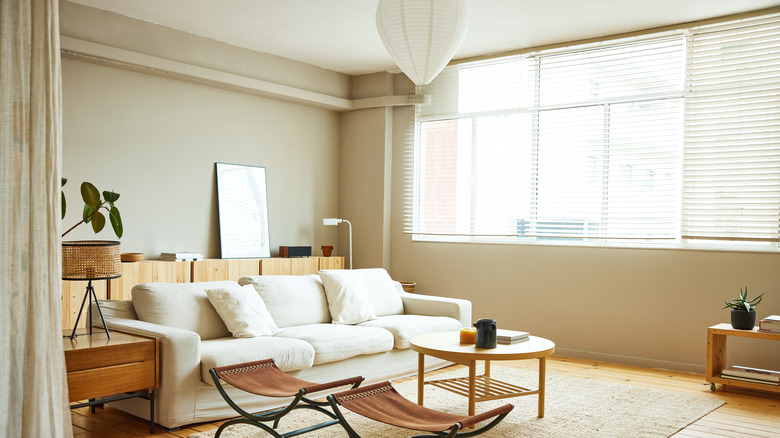 Modern living room with wooden furniture and white blinds open