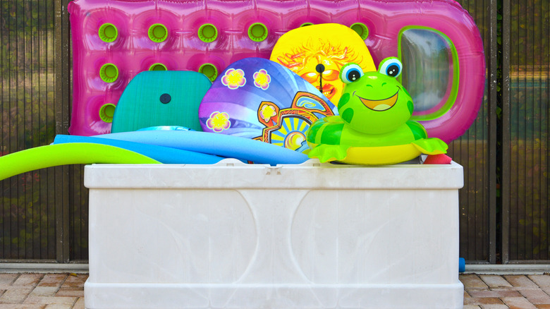 Poolside storage bin filled with pool toys