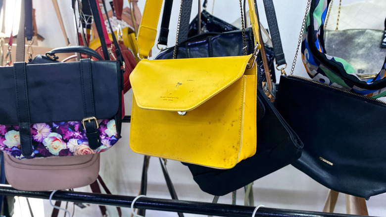 Assorted hand bags hanging on hooks at a thrift store.