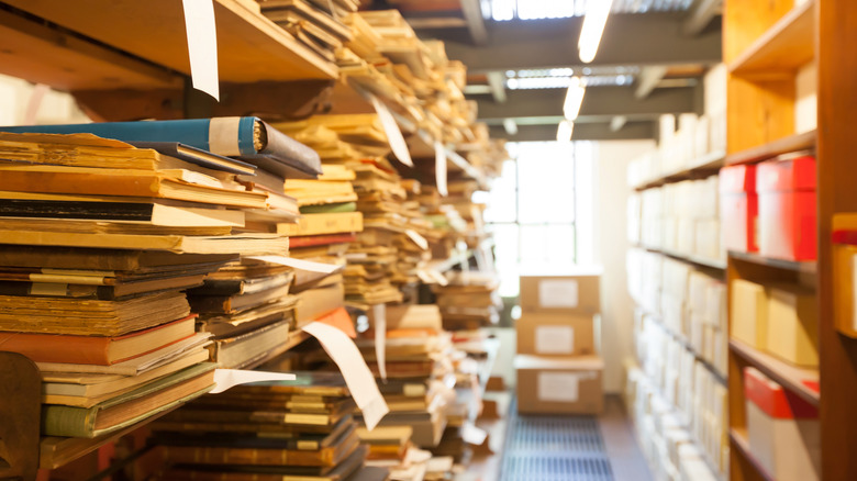 Old papers, files, documents piled high on shelves in a secondhand store.