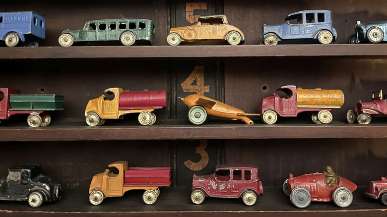 Vintage 1920s toy cars and trucks made of tin on a shelf in a store.
