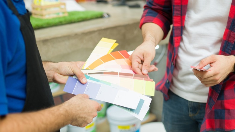 A person looking at color swatches with paint store employee