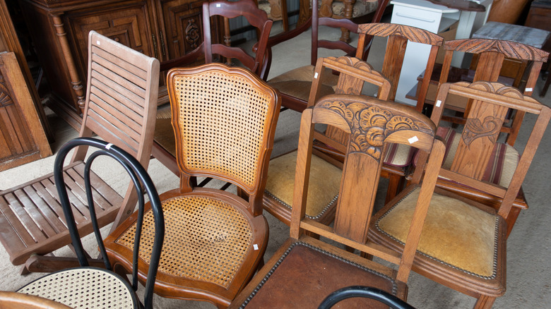 A variety of vintage wooden dining chairs are ready to be purchased at a thrift store.