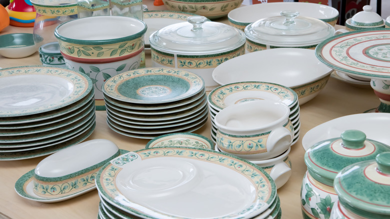Pile of decorative plates and bowls on a table at a yard sale