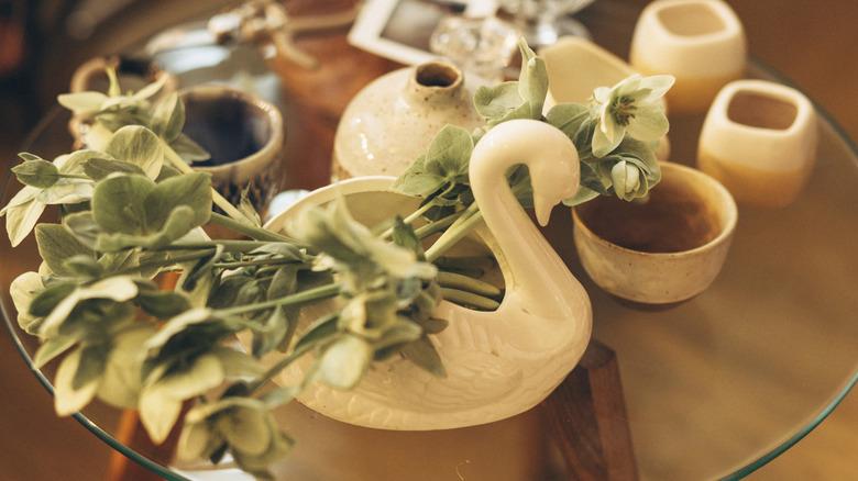 A swan vase on a table alongside other ceramic items
