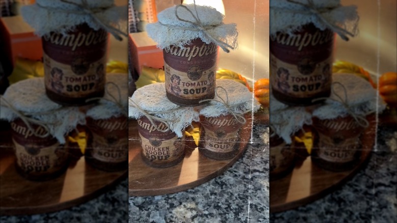 Three vintage Campbell's Soup cans with lace and twine wrapped around the top