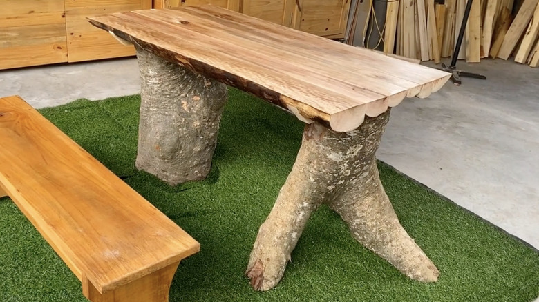 A rustic outdoor table made from tree stumps and logs