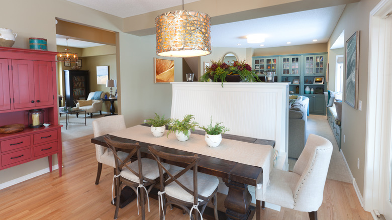 Dining room table underneath large light next to living room