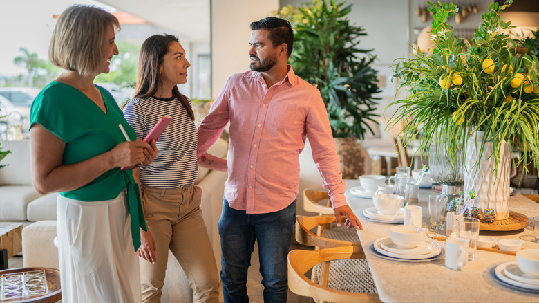 A couple shopping for dining room table and talking with salesperson
