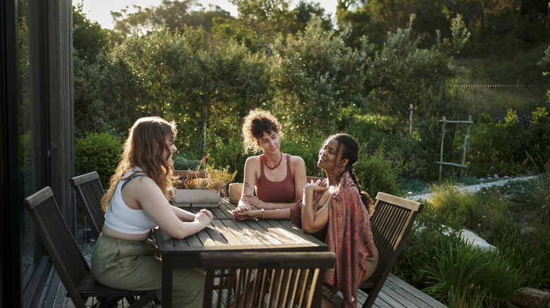A group of women talking around a patio table.