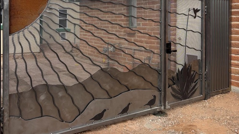 A grille gate with a desert landscape design as a main feature.