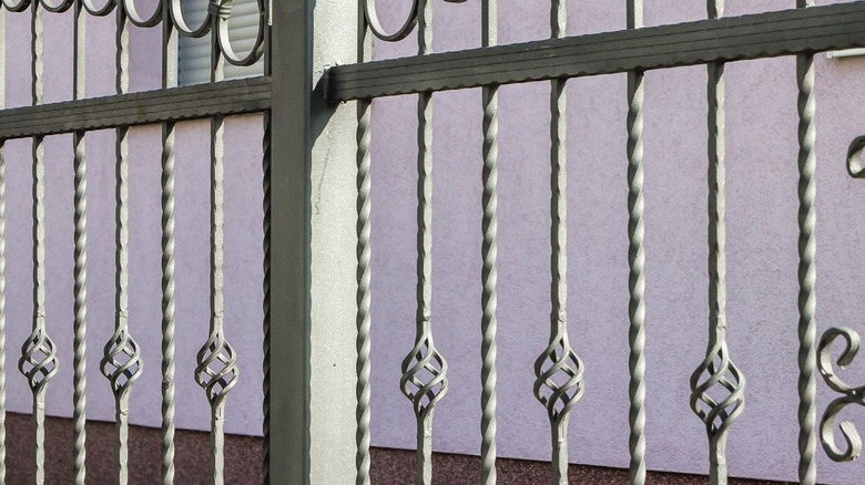 A gate with basket twist wrought iron vertical bars.