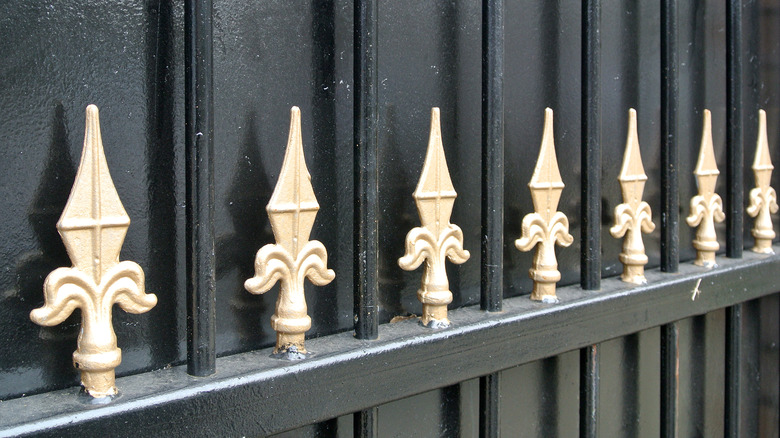 A close up of brass hot stamped spear points on a grille gate.