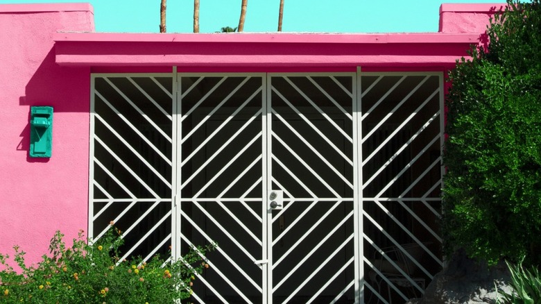 A geometric grille gate on a pink house in the desert.