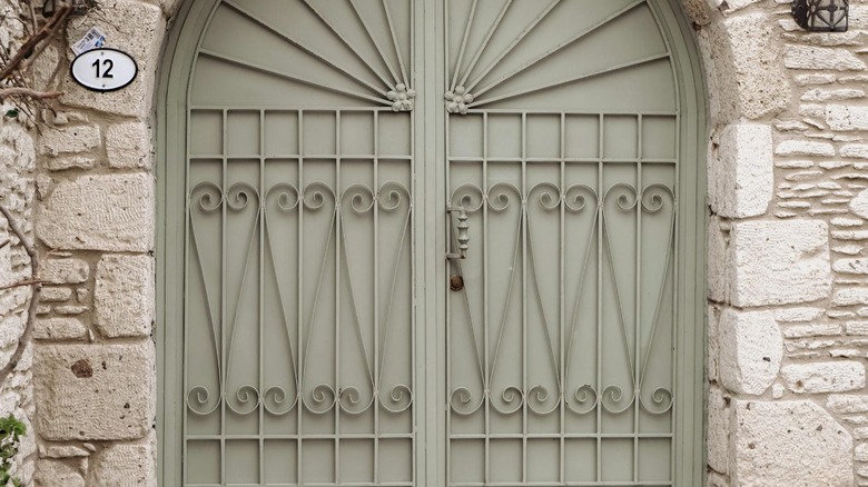 A green powder-coated scroll heart grille gate over a rounded exterior door.