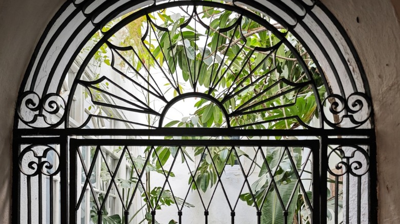 A painted blue, sunburst grille gate leading to an indoor garden