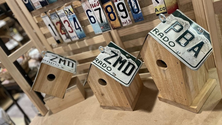 Two wooden birdhouses on a table, a Colorado license plate on each as the roof