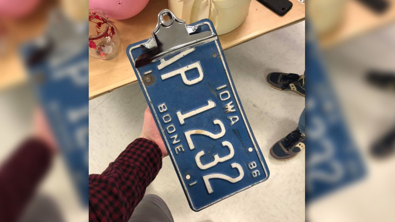Hand holding a clipboard made of a license plate