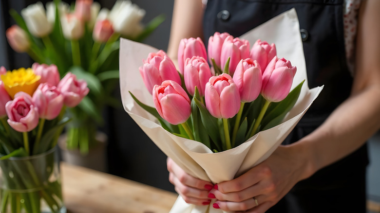 Person holding wrapped pink tulip bouquet