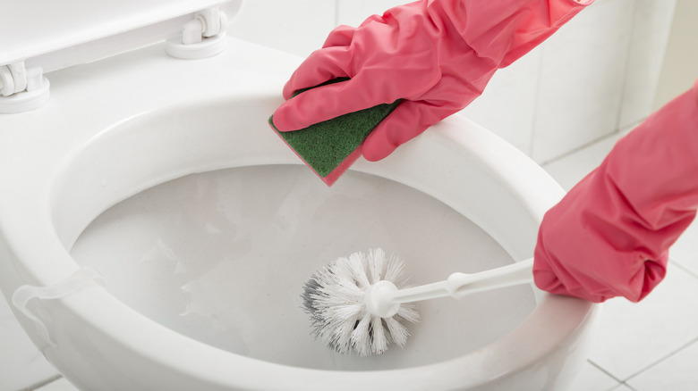 rubber gloved hands cleaning toilet