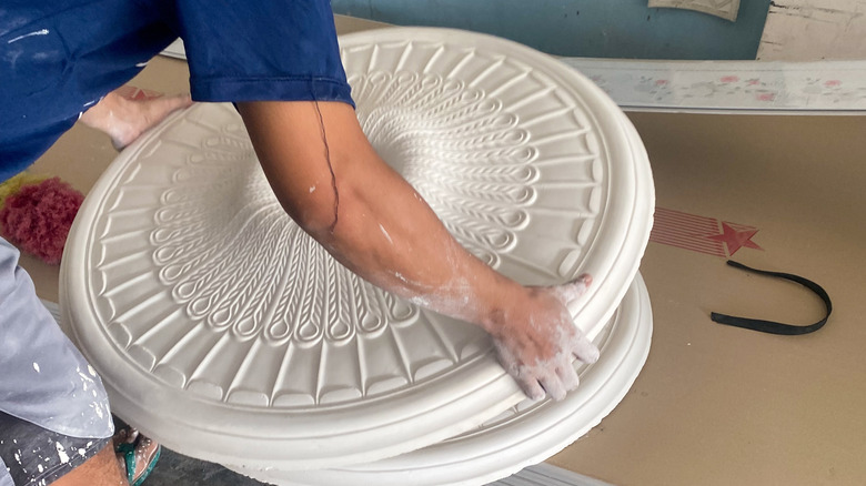 A workman handling ceiling medallion to install