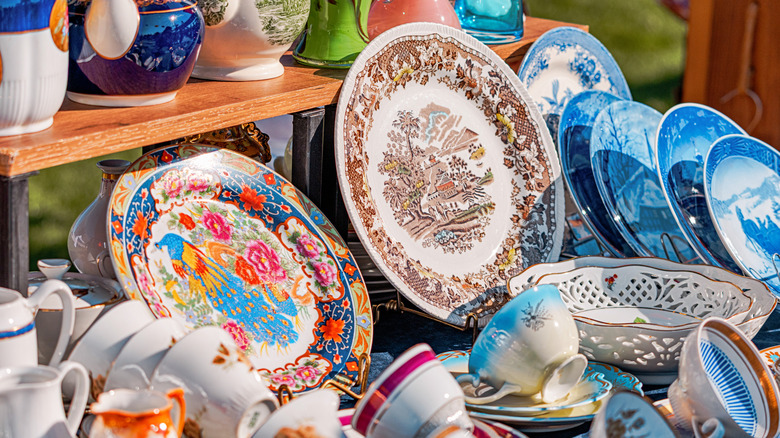 A collection of vintage plates and cups at an outdoor market